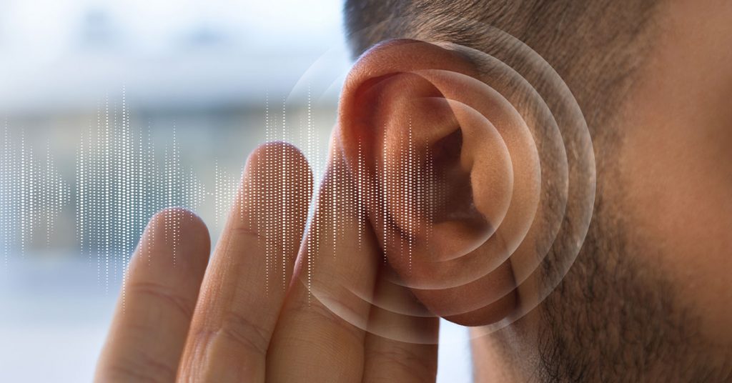 Imagen en primer plano de un oído humano con ondas sonoras digitales ilustradas alrededor, representando la percepción auditiva o la detección de sonidos sutiles